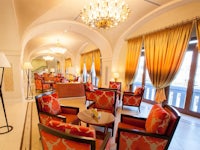 a lobby with orange chairs and a chandelier