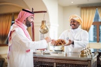 two men are serving food in an arabic restaurant