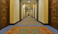 a hallway in a hotel with a blue carpet and wooden doors