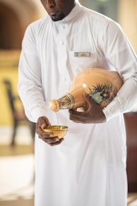 a man in a white robe holding a bottle of water