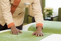 a man is making a bed in a hotel room