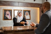 a woman in a hijab greeting a man at a hotel